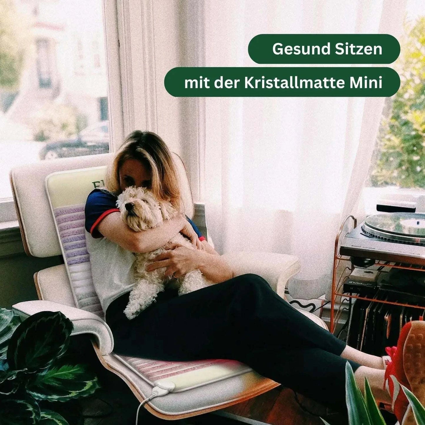 Frau sitzt mit Hund auf der Kristallmatte Mini 2.0 von Elvari, ideal für gesundes Sitzen im Alltag mit wohltuender Wärme.